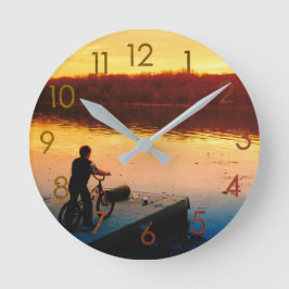 Jungen auf einem Fahrrad bei Sonnenuntergang Wandu Runde Wanduhr