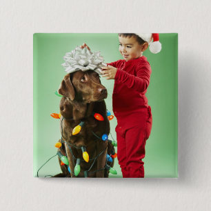 Junger Junge, der Weihnachtslichter um einen Hund Button
