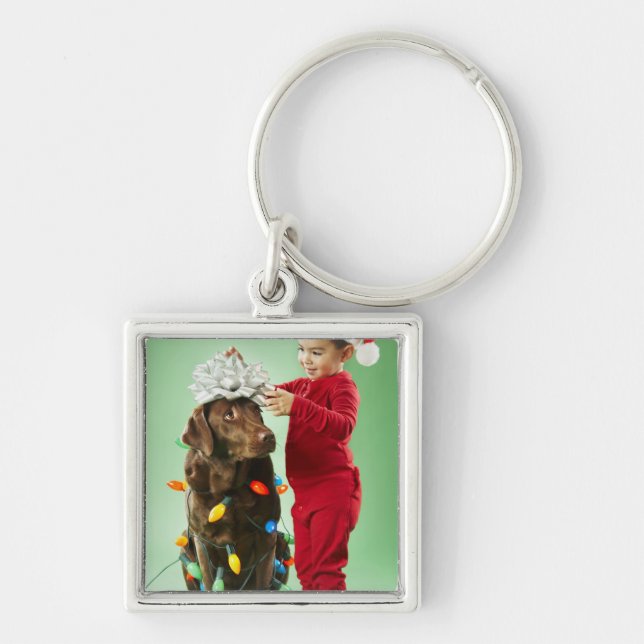 Junger Junge, der Weihnachtslichter um einen Hund Schlüsselanhänger (Vorne)