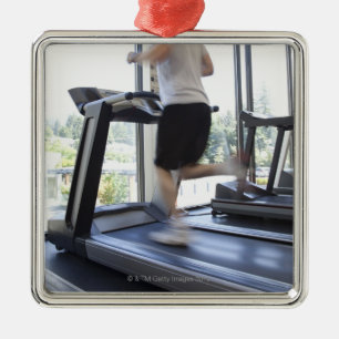 Junger Mann, der auf eine Tretmühle am Ornament Aus Metall