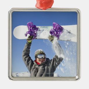 Junger Mann, der seinen Snowboard über seinem Kopf Silbernes Ornament