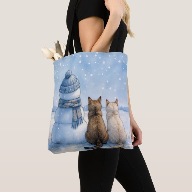 Katzensitzend mit einem Schneemann auf einem Feld (Von Nahem)
