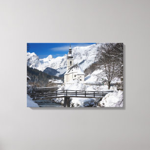 Kirche im Schnee mit den Alpen Leinwanddruck