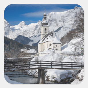 Kirche im Schnee mit den Alpen Quadratischer Aufkleber