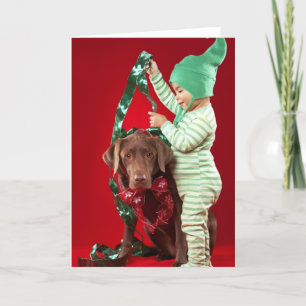 Kleiner Junge, der einen Hund verziert Feiertagskarte