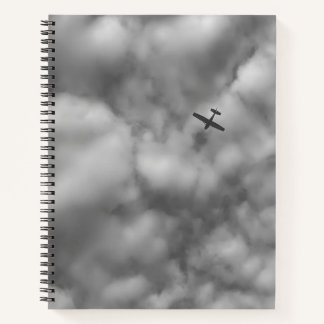 Kleines Flugzeug fliegt in bewölktem Himmel Foto Notizbuch