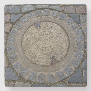Kopfsteinpflasterstraße mit Manhole, grau-braun Steinuntersetzer
