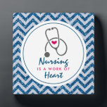 Krankenpflege ist ein Werk von Heart Sprichwort w/ Fotoplatte<br><div class="desc">Eine Foto-Plakette mit einem blauen Zickzack Imitat Glitzer-Muster. Nicht der eigentliche Glitzer,  nur ein Bild. Oben liegt ein weißer Rahmen und innen ist das Sprichwort: Die Pflege ist ein Herzstück mit einem kleinen roten Herz und einem grauen Stethoskop.</div>