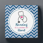 Krankenpflege ist ein Werk von Heart Sprichwort w/ Fotoplatte<br><div class="desc">Eine Foto-Plakette mit einem blauen Zickzack Imitat Glitzer-Muster. Nicht der eigentliche Glitzer,  nur ein Bild. Oben liegt ein weißer Rahmen und innen ist das Sprichwort: Die Pflege ist ein Herzstück mit einem kleinen roten Herz und einem grauen Stethoskop.</div>