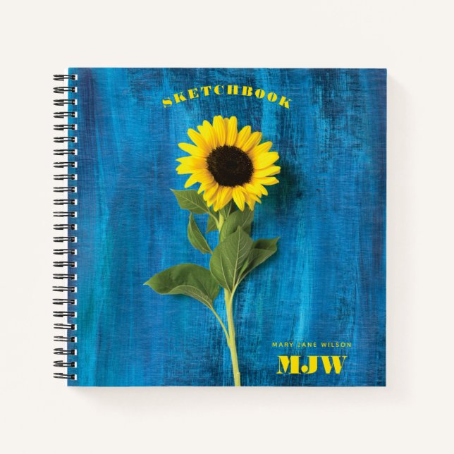 Lebhafte Sonnenblume und Monogramm auf blauem Hint Notizbuch (Vorderseite)