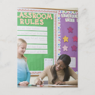 Lehrerin bewertet Mädchenpapier im Klassenzimmer Postkarte
