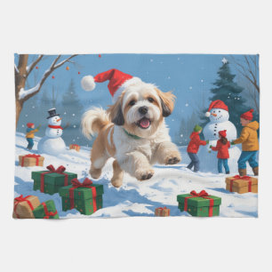 Lhasa Apso läuft im Schnee mit Weihnachtsmütze Geschirrtuch