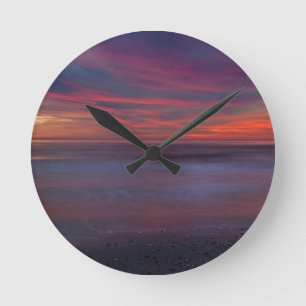 Lila-farbener Sonnenaufgang an der Meeresküste Runde Wanduhr