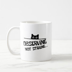 Lustige schwarze hinterlistige Katze beobachtet, s Kaffeetasse