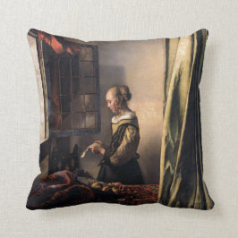 Mädchen-Lesebuchstabe am offenen Fenster durch Kissen