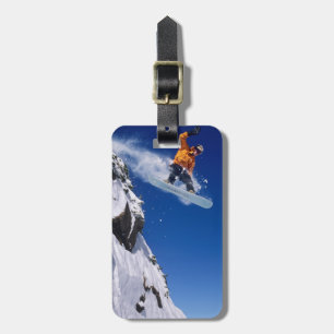 Mann auf einem Snowboard, der von einem Gesims spr Gepäckanhänger