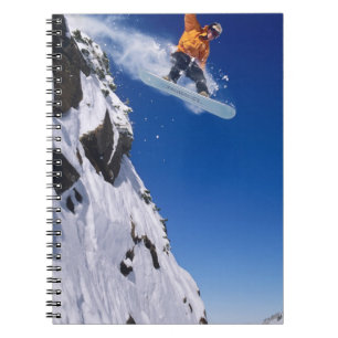 Mann auf einem Snowboard, der von einer Schneekorn Notizblock