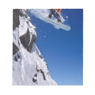 Mann auf einem Snowboard springt von einem Kornfle Notizblock