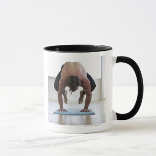 Mann, der Training auf Yogamatte tut Tasse