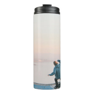 Mann mit blauem Skateboarding an der Wand am Stran Thermosbecher