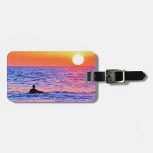 Mann sieht sich das Gepäckanhänger bei Sonnenunter