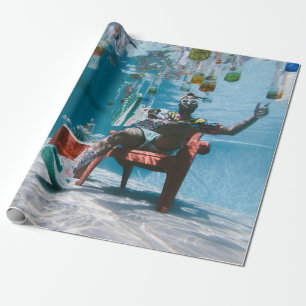 Mann sitzt auf Stuhl unter Wasser mit schwimmendem Geschenkpapier
