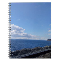 Meeresufer und Bahngleis unter blauem Himmel