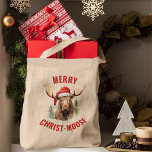 Merry Christ-moose Funny Christmas Moose Tragetasche<br><div class="desc">Genießen Sie den Urlaubssinn mit unserer bezaubernden Weihnachtsfeiertagstasche, die mit einem lieblichen Elch an einer Weihnachtsmannmütze vorne verbunden ist, begleitet von dem sonnigen Gruß "Fröhlicher Christ-Elch". Diese Tasche ist das perfekte Lachen und Freude während der Festsaison. Das skurrile Design und das clevere Wortspiel machen es zu einer einzigartigen und reizvollen...</div>