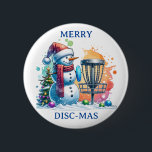 Merry Disk-mas | Disk Golf Christmas Button<br><div class="desc">Niedlicher Cartoon Snowman in Weihnachtsmannmütze neben einem Discgolf im Schnee neben einem Weihnachtsbaum.</div>
