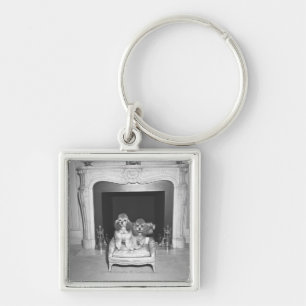 Miniaturpudel, die vor Kamin sitzen Schlüsselanhänger