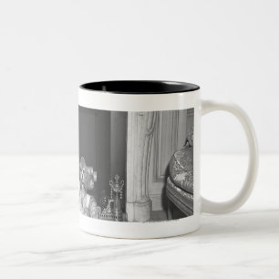 Miniaturpudel, die vor Kamin sitzen Zweifarbige Tasse