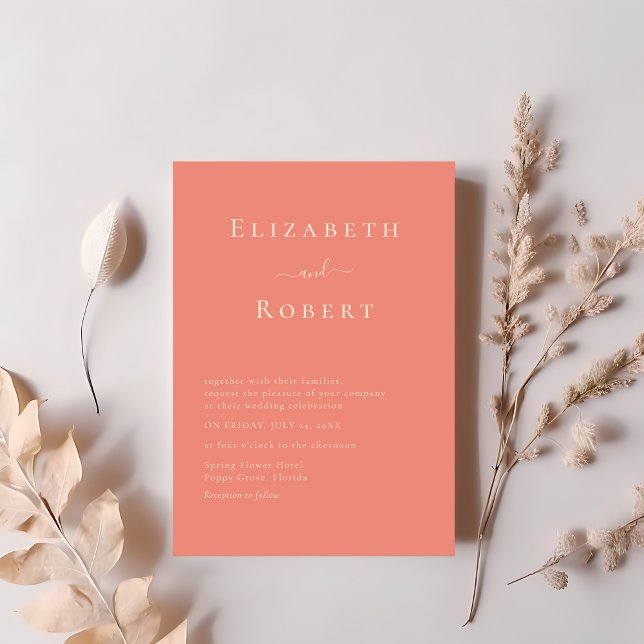 Moderne Chic Coral Minimalistisch Script Wedding Einladung (Modern Chic Coral Minimalist Script Wedding Invitation on a table next to dry soft pink flowers.)
