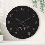 Modernes Schwarzes Gold Feminin Script Mit Monogra Runde Wanduhr<br><div class="desc">Modernes Schwarzes Gold Feminine Script Mit Monogramm große Uhr. Diese elegante,  große Uhr lässt sich einfach mit Ihrem eigenen Monogramm und Namen personalisieren.</div>