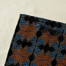 Monarchschmetterling weht nach orangefarbenem und  strandtuch