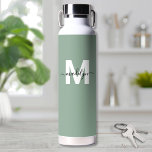 Monogram Trinkflasche<br><div class="desc">Erstellen Sie Ihre eigene Personalisiert Sage Green Name Monogram Water Flasche. Diese niedliche und stilvolle Wasserflasche bietet einen weichen, grünen Hintergrund für eine erdige, beruhigende Atmosphäre. In der Mitte befindet sich ein fett weißer Initial, überlagert durch einen fließenden schwarzen Skriptnamen für eine personalisierte Touch auf beiden Seiten. Ideal für Schüler,...</div>