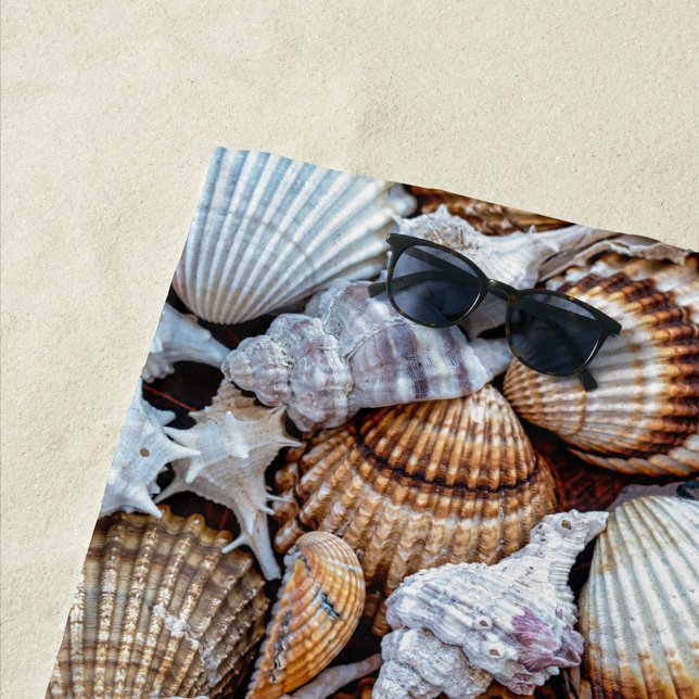 Muscheln Strandtuch (A vibrant collection of seashells scattered across a sandy surface. )