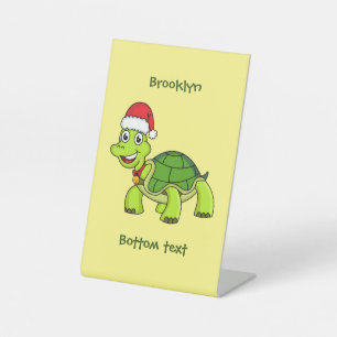 Niedliche glückliche Schildkröte mit Weihnachtsman Sockelschild