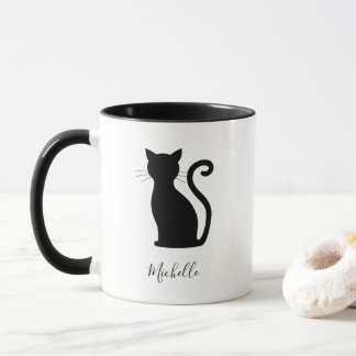 Niedliche schwarze Katze mit schwarzem und weißem Tasse