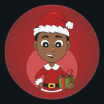 Niedlicher afrikanischer Weihnachtsjunge Cartoon Runder Aufkleber<br><div class="desc">Rundaufkleber mit einer Illustration eines niedlich lächelnden afroamerikanischen Jungen mit kurzem schwarzem Haar trägt der Junge ein Weihnachtskostüm mit einem roten Hut und hält ein Geschenk; in einem roten Kreis auf einem roten Hintergrund ein Weihnachtsferien-Design</div>