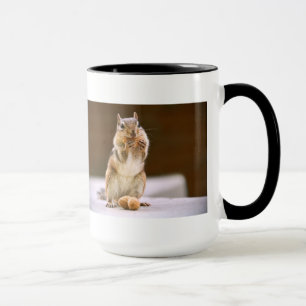Niedlicher Chipmunk, der eine Erdnuss isst Tasse