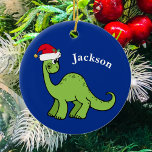 Niedlicher Weihnachtsdinosaurier Custom Kids Blue Keramik Ornament<br><div class="desc">Phantastischer grüner Dinosaurier lächelt und sieht sehr niedlich in einem Urlaub roten Weihnachtsmann Hut. Passen Sie dieses bezaubernde Weihnachtsgeschenk mit dem Namen des Empfängers an,  um es noch personalisierter zu machen. Cooler kleiner Junge für ein Kind.</div>