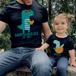 Niedliches Aquamarines Baby Dino Name Vater Kinder T-Shirt<br><div class="desc">Individuelles Textdesign mit einem niedlichen aquamarinen Baby T-Rex in einer Ei-Muschel,  die ein Herz hält. Finden Sie ein passendes Dinosaurier-Shirt in meiner Sammlung "Daddy and me designs".</div>