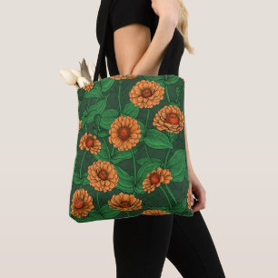 Orange Zinnia Blume, grüne Blätter auf dunkelgrün