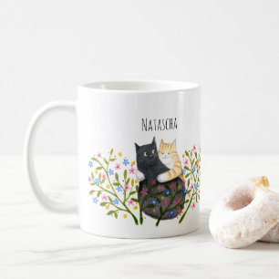 Orangene getigerte Katze und schwarze Katze in Blu Kaffeetasse