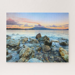 Ozeansonnenuntergang mit sanften Wellen und Vulkan Puzzle