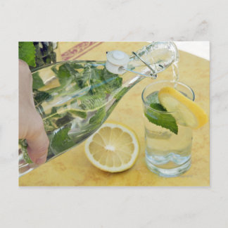Person, die Wasser (mit Minze gefüllt) in ein Glas Postkarte