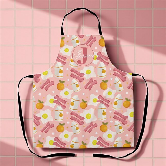 Personalisiertes Retro-Breakfast-Muster Schürze (Whimsical pink apron with fried eggs, bacon, milk, and oranges for sunny breakfast vibes.)
