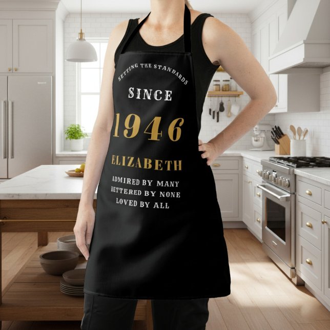 Personalized 80th Birthday 1946 Black & Gold Schürze (1946 birthday apron in black and gold worn in a kitchen.)