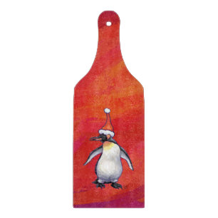 Pinguin in Weihnachtsmannmütze auf Rot Schneidebrett