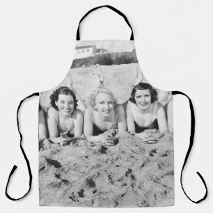 Porträt von fünf jungen Frauen, die am Strand lieg Schürze